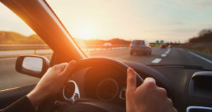 hands on a steering wheel looking through windshield at divided highway